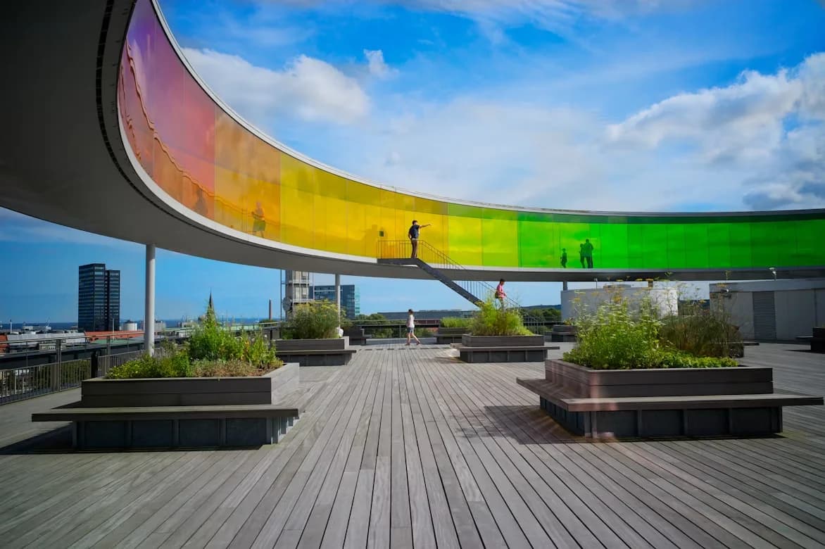 A circular, rainbow-colored panoramic walkway by artist Olafur Eliasson sits atop the ARoS Aarhus Kunstmuseum, offering a unique, 360-degree view of the city.