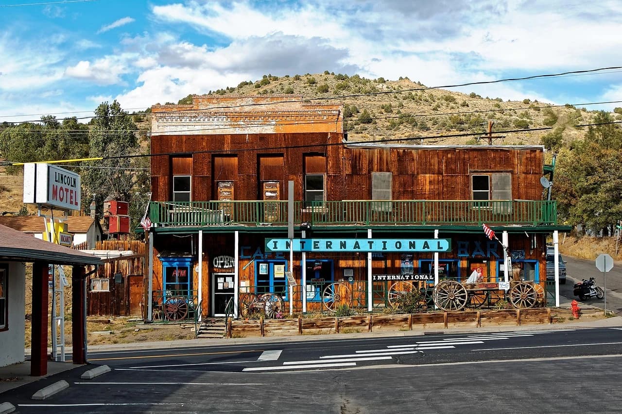 A historic, rustic building with a sign that says "International Bar" stands on a dusty street in a small town.