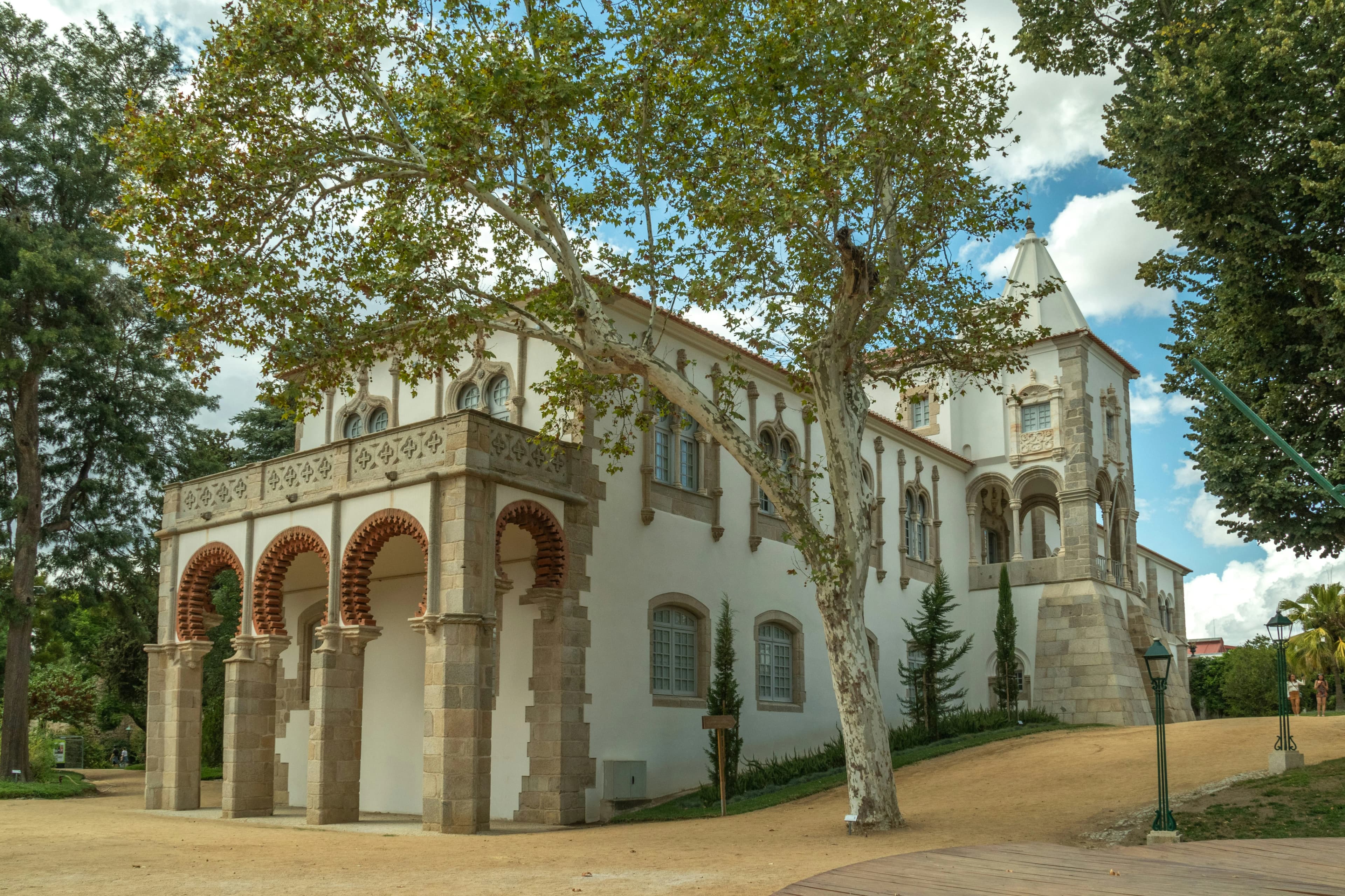 The Palácio de Dom Manuel, a historic palace with distinct architectural features and large arched windows, surrounded by trees.