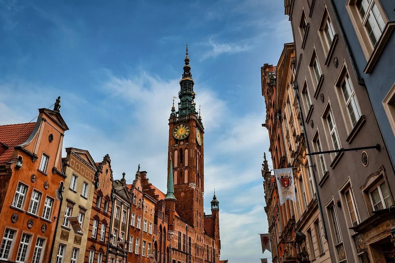 The Main Town Hall of Gdansk, with its tall clock tower and elegant facade, rises above the historic buildings of the Long Market.