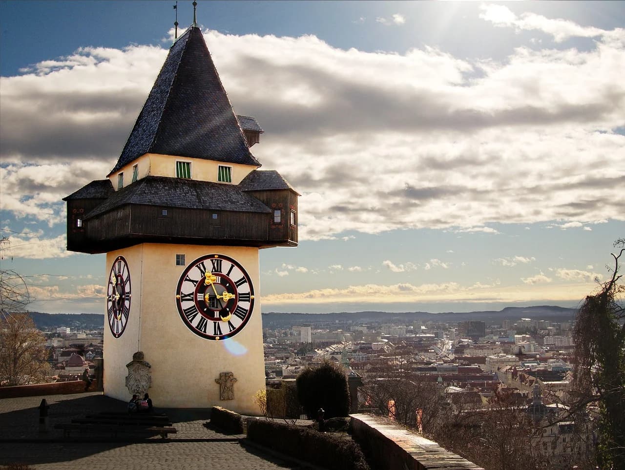 The iconic Uhrturm, or Clock Tower, a medieval landmark with a unique clock face, overlooks the city of Graz from atop a hill.