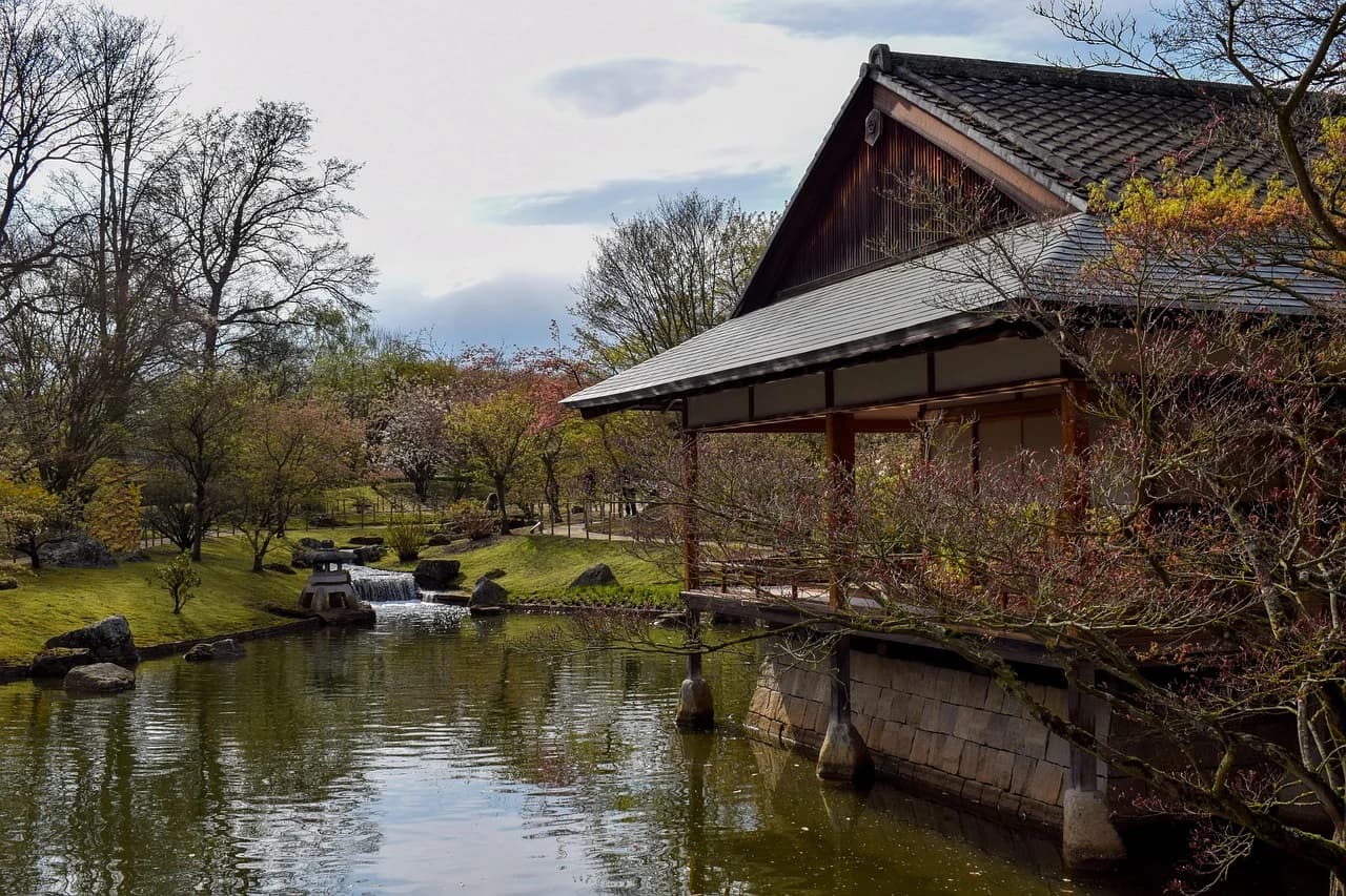 A traditional Japanese teahouse is set beside a tranquil stream and a pond in the Japanese Garden of Hasselt.