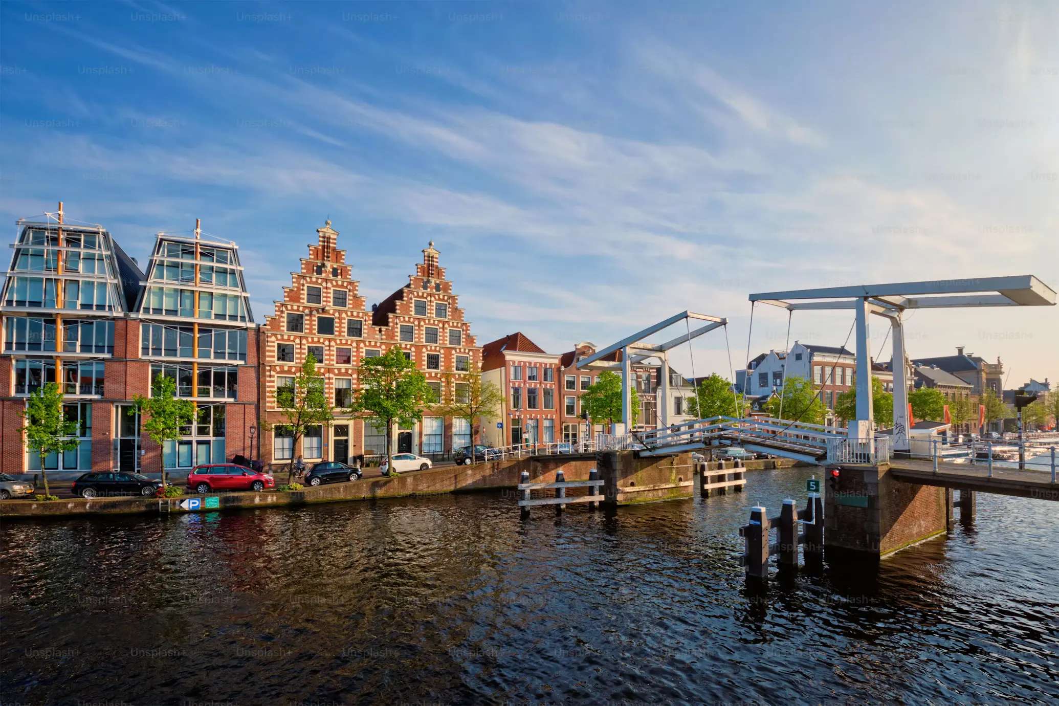 Traditional Dutch gabled houses stand along a canal, with a classic drawbridge in the foreground.