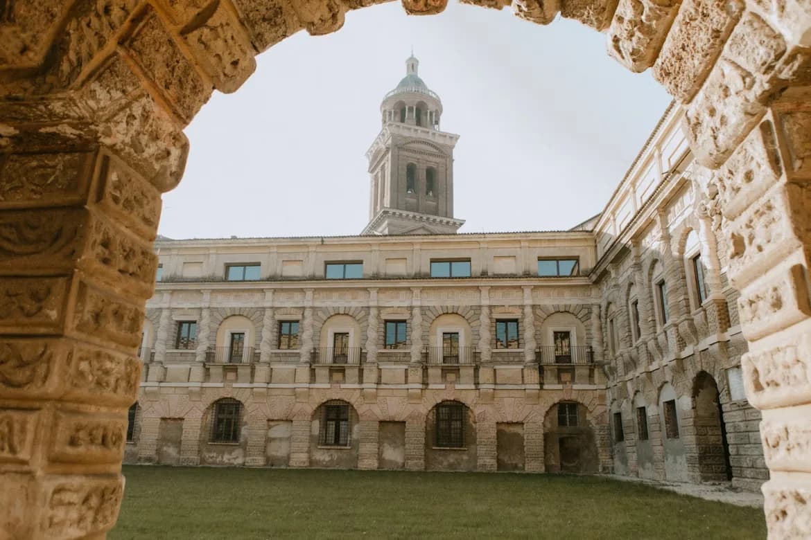A stone archway provides a framed view of a historic courtyard and a tall clock tower.