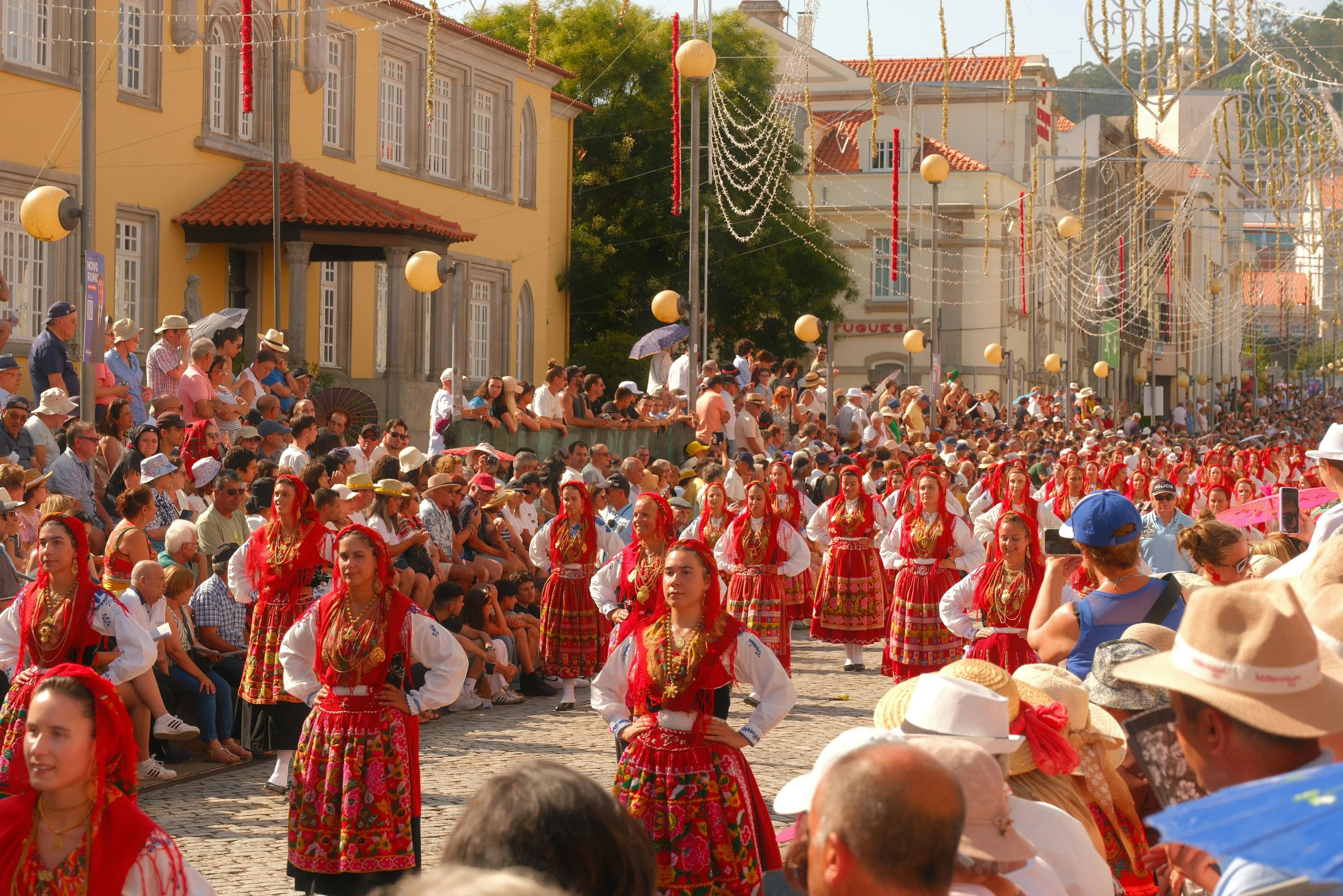 A crowd of people in traditional dress and colorful headscarves participates in a street procession.