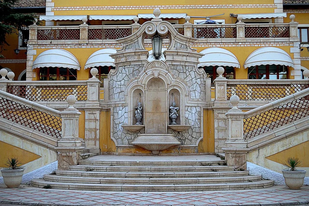 A historic fountain with a stone staircase and statues is a beautiful feature of a building courtyard.