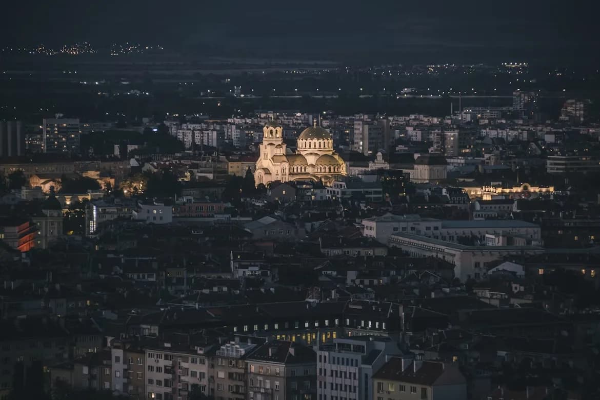 The illuminated domes of the Alexander Nevsky Cathedral rise above the city lights of Sofia at night.